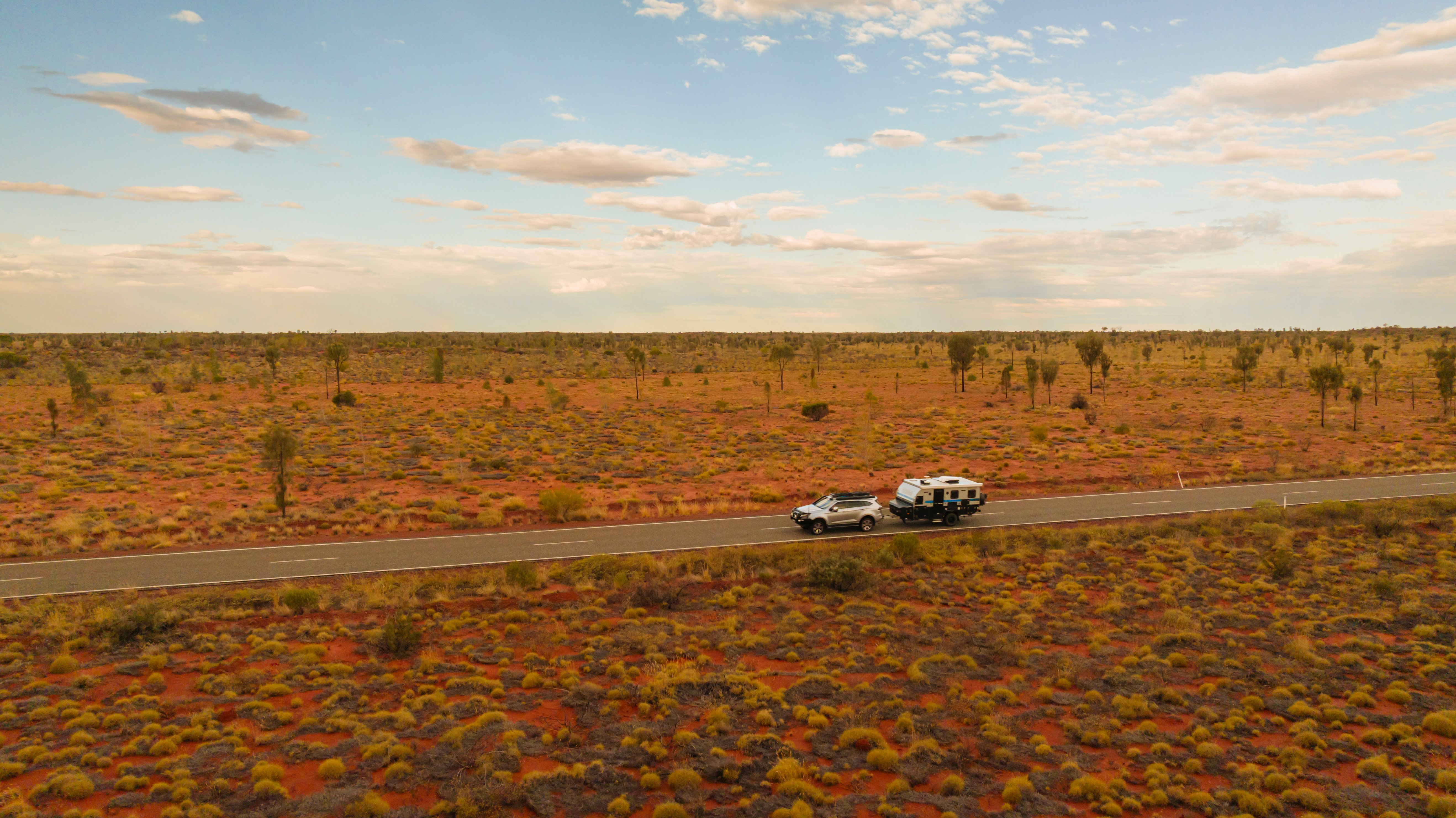 car with camper driving down a desert road